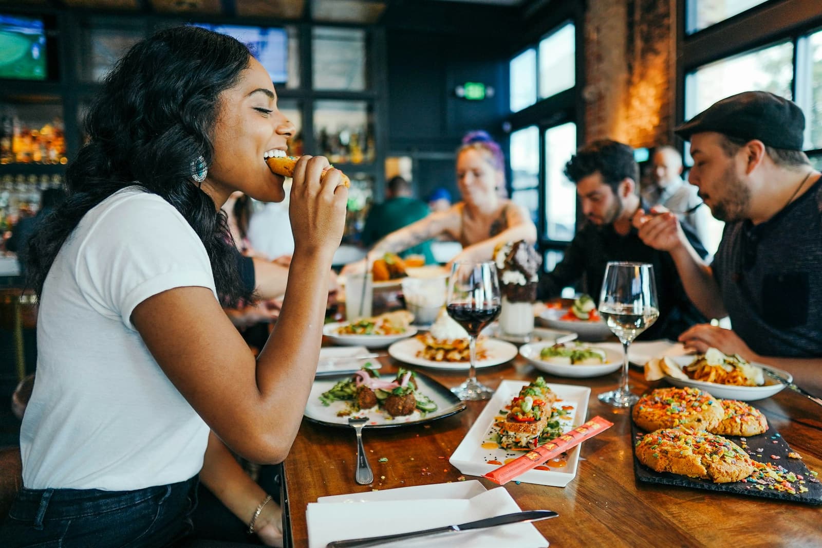 A woman laughing while eating with friends at a busy restaurant table